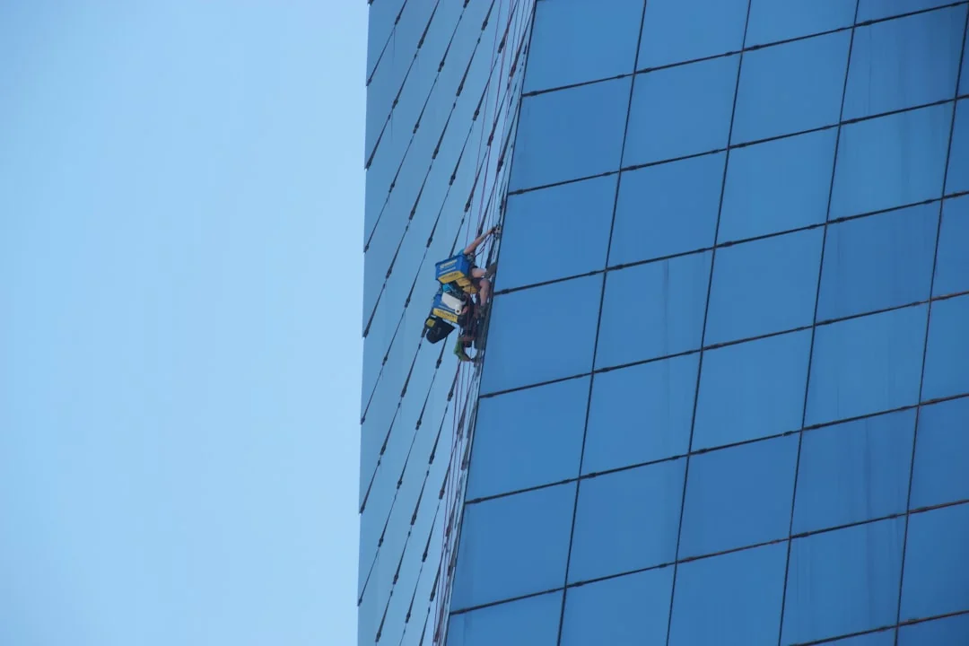 A person in protective gear sanitizing an office desk using fumigation equipment during daytime.